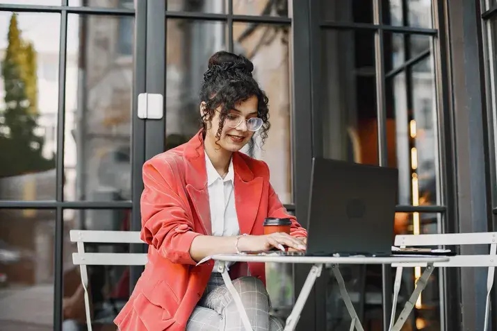 Woman working on laptop outdoors with coffee and digital marketing tasks