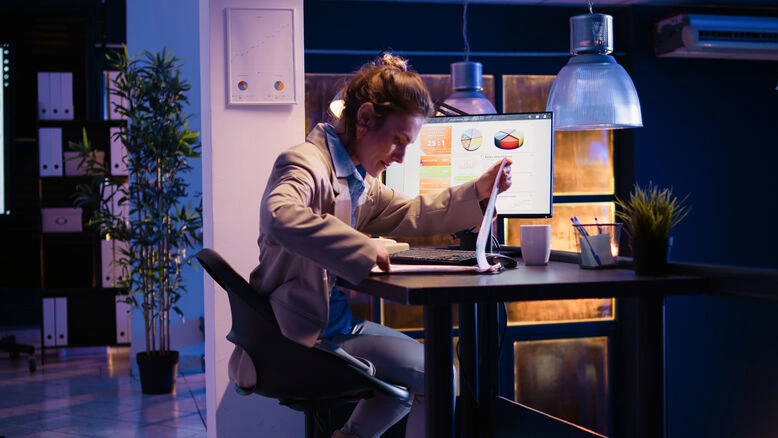 Professional woman analyzing business charts on computer in modern office workspace