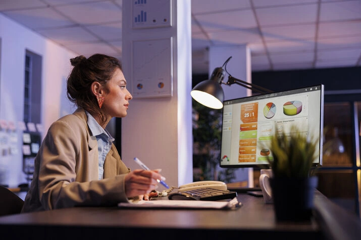 Businesswoman reviewing analytics dashboard on desktop computer in office environment