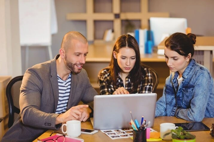 Group discussion analyzing data on laptop in office