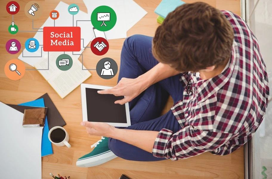 Person using a tablet while managing social media marketing and online communication from a home workspace.